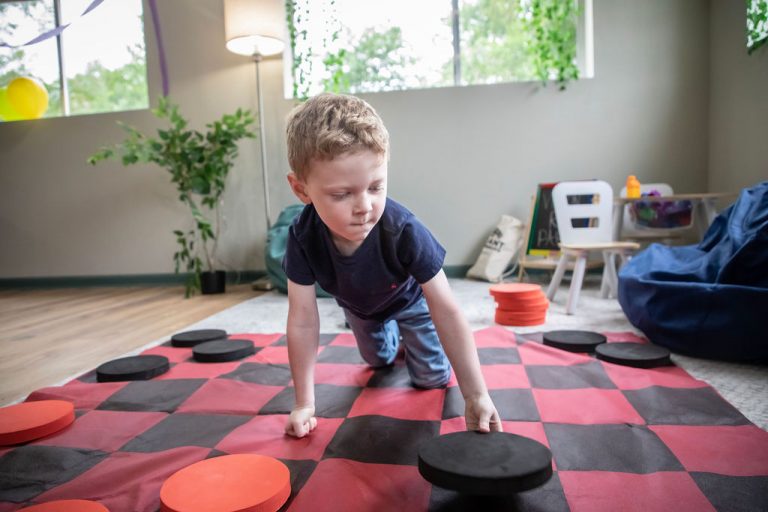 Boy playing giant checkers on the floor