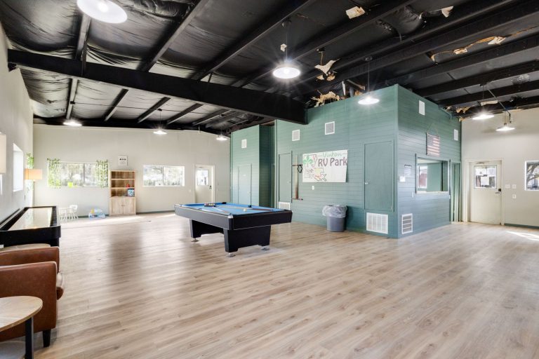 Vinton LA RV Park Vinton LA RV Park recreation room in Vinton Texas with wood floors, pool table, play area, toys, chairs, windows and green sign.