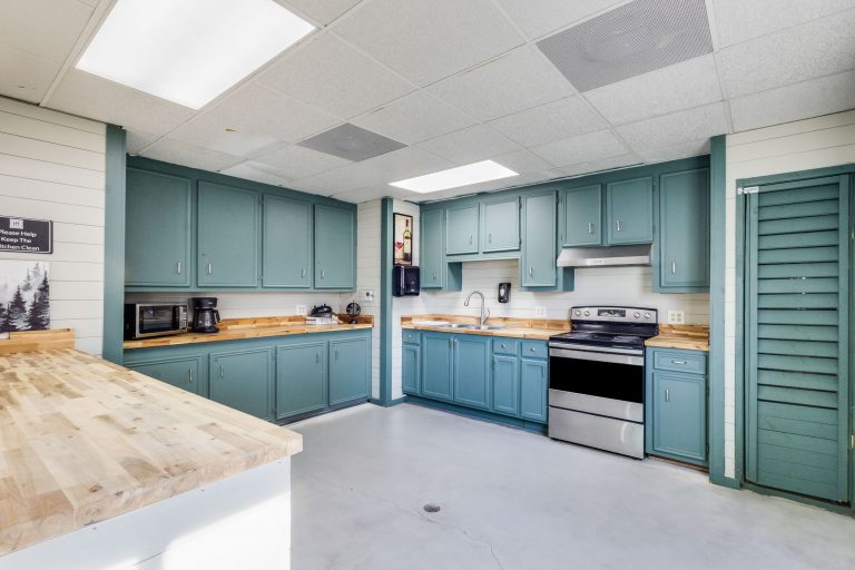 Vinton LA RV Park Modern kitchen at Vinton LA RV Park in Vinton, Texas, with teal cabinets, wood countertops, stainless steel appliances, bright lighting.