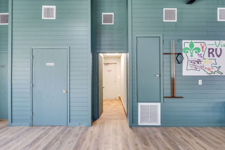 Vinton LA RV Park Vinton LA RV Park interior in Vinton, Texas: teal wall, two closed doors, wood floor, colorful fleur-de-lis scout poster.