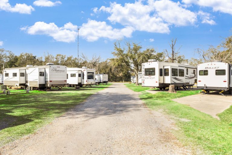 Vinton LA RV Park Vinton LA RV Park in Vinton, Texas with rows of white RVs on grassy lots, gravel road, trees, and a partly cloudy blue sky.