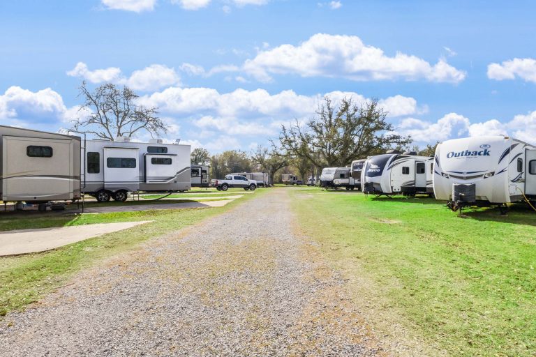 Vinton LA RV Park Vinton RV Park in Vinton Texas with a gravel road between RVs and trailers on grassy lots, trees, and partly cloudy sky.